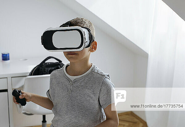 Boy wearing virtual reality simulator playing video game at home