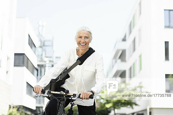Happy businesswoman commuting to work through bicycle