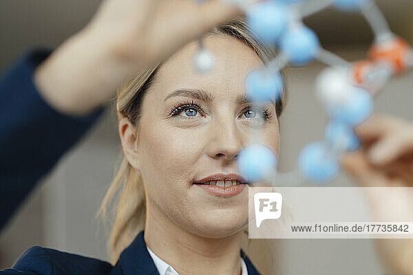 Lächelnde Geschäftsfrau untersucht molekulares Modell im Büro