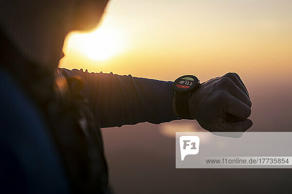Mann überprüft Smartwatch bei Sonnenuntergang