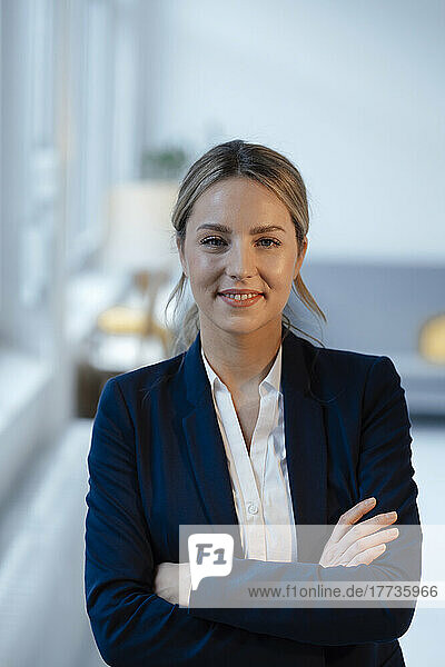 Smiling beautiful businesswoman with arms crossed in office