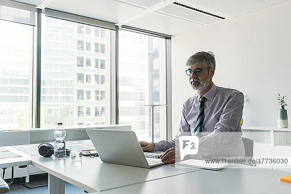 Businessman using laptop sitting at desk in office