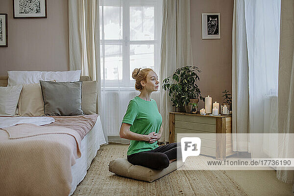 Woman sitting cross-legged practicing yoga at home