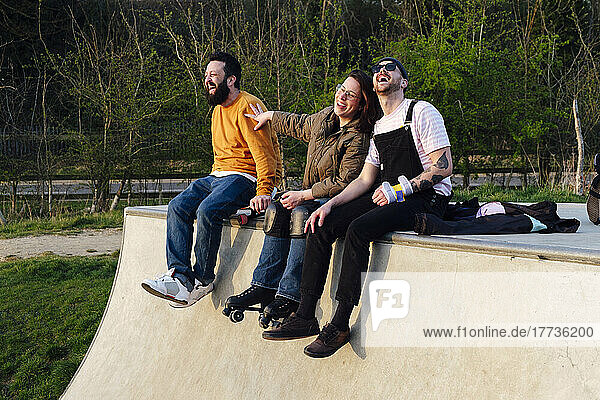 Happy friends enjoying sitting on ramp in skate park