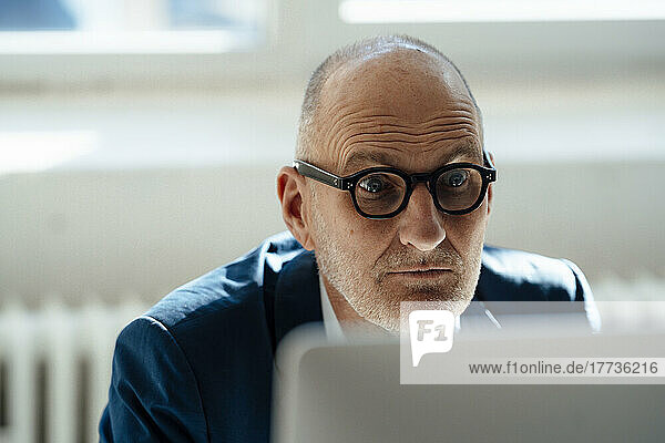 Senior businessman staring at computer monitor in office