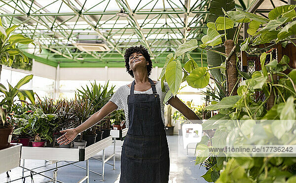 Carefree gardener with arms outstretched enjoying by plants at nursery
