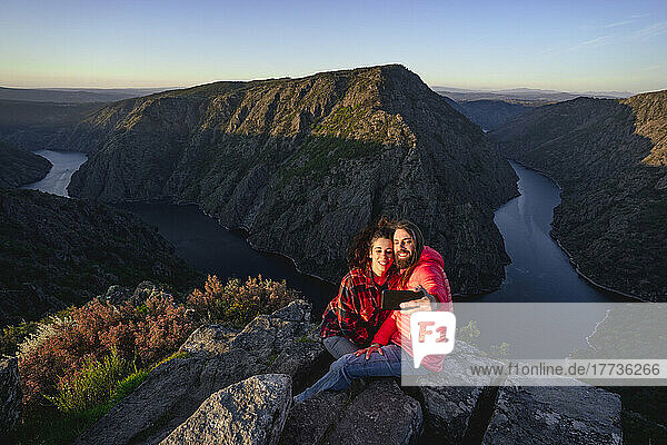 Happy couple taking selfie through smart phone on top of mountain