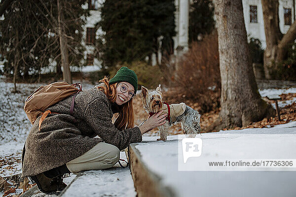 Happy woman with pet dog leaning on steps
