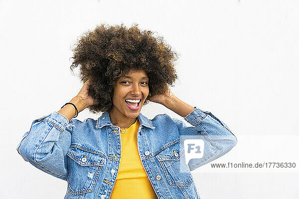Happy Afro woman standing with hands in hair