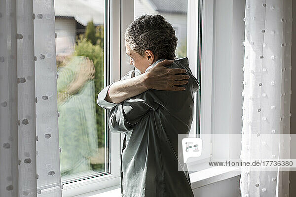 Mature woman standing at the window at home
