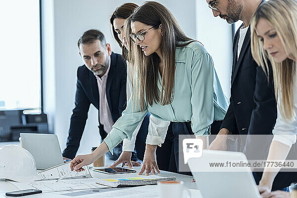 Businesswoman discussing over documents with colleagues in meeting at office
