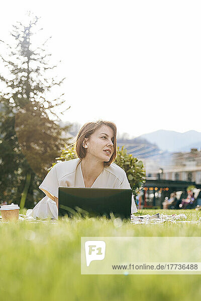 Woman with laptop lying at park