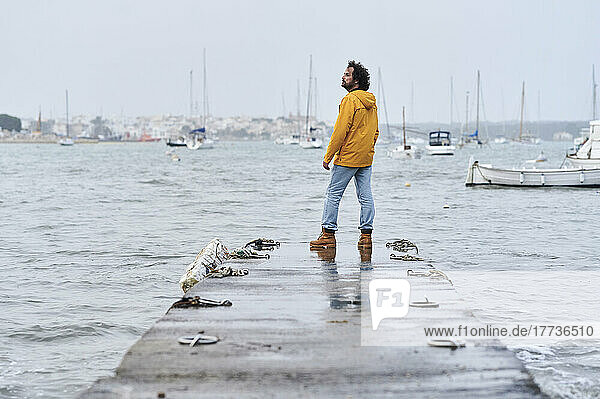 Contemplative man standing on jetty in front of sea