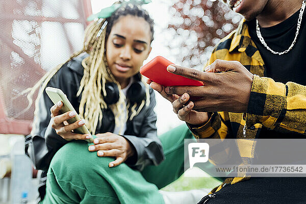 Young man using smart phone sitting by woman