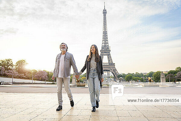 Happy mature couple holding hands and walking in front of Eiffel Tower  Paris  France