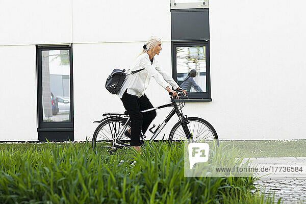 Mature businesswoman commuting to work on bicycle