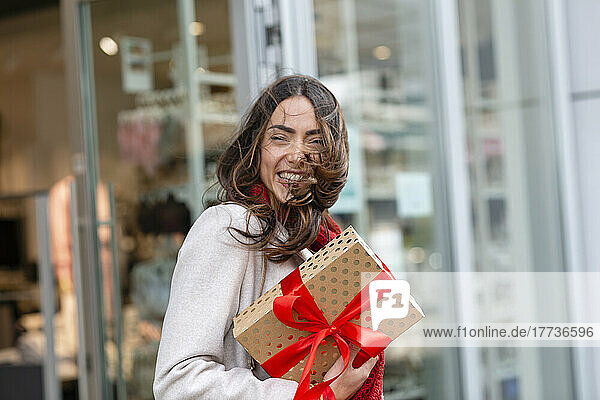 Happy woman with tousled hair holding Christmas present