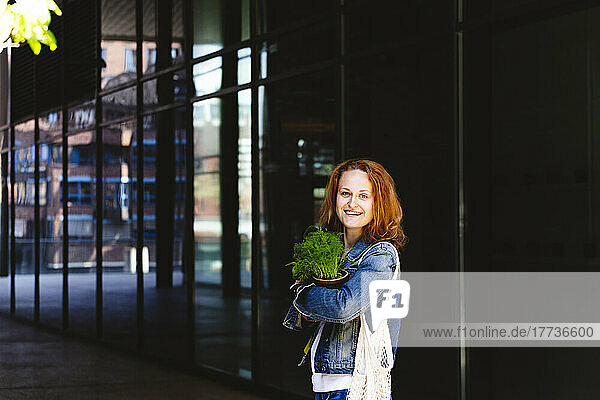 Smiling woman standing with dill plant in arcade