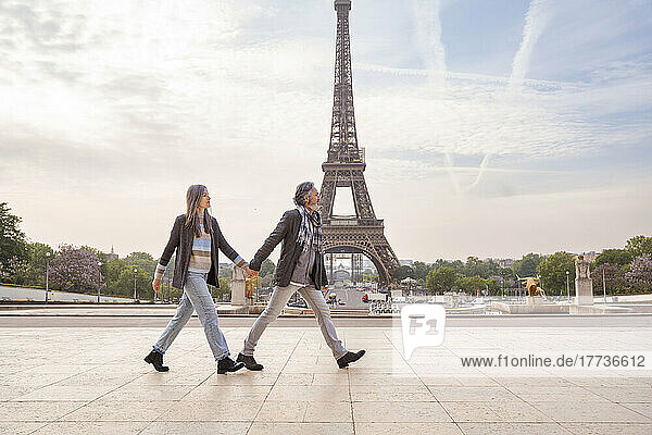 Mature couple holding hands and walking in front of Eiffel Tower  Paris  France