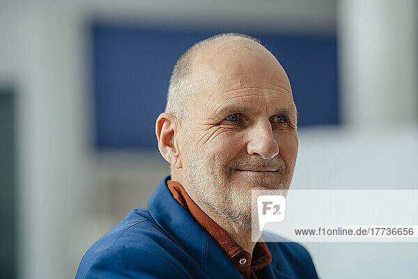 Smiling senior businessman looking away in office