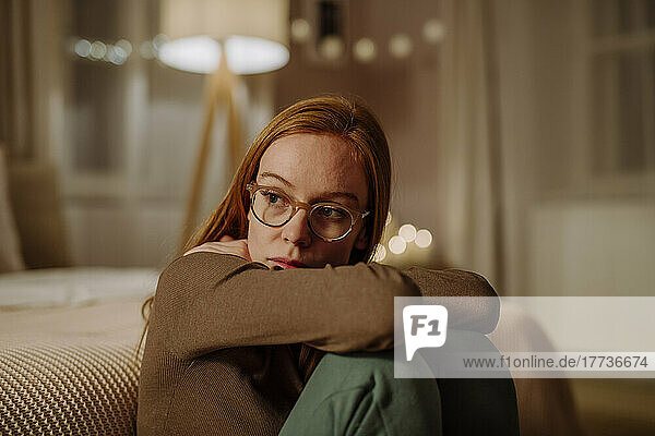 Traurige rothaarige Frau sitzt zu Hause vor dem Bett