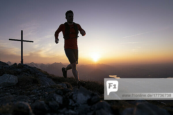 Silhouette man running on top of Sauling mountain at sunset