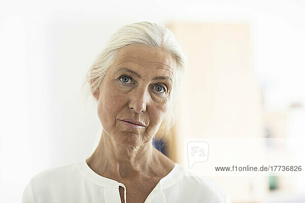 Contemplative mature woman with white hair at home
