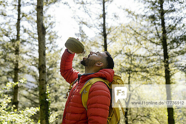 Man drinking water standing in forest