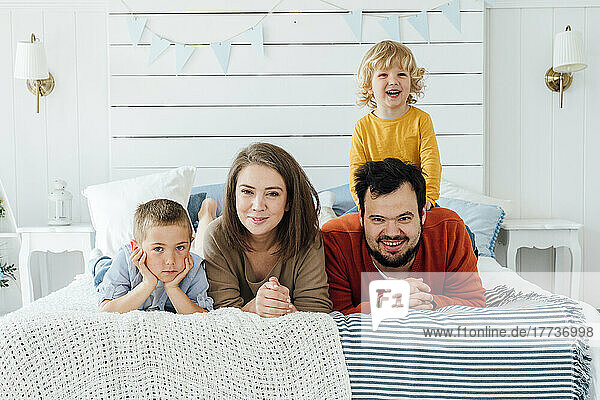 Happy family lying together on bed at home