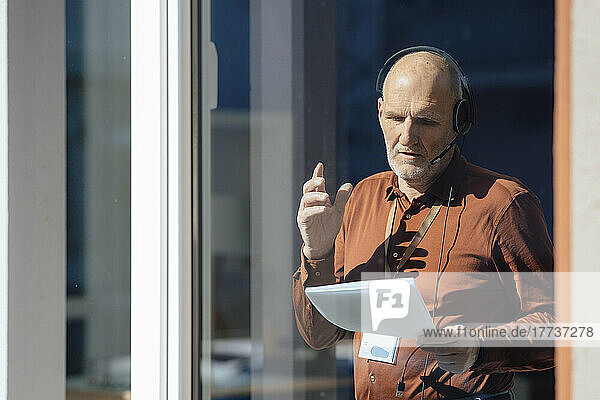 Businessman wearing headset analyzing document seen through glass