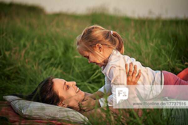 Smiling mother and daughter lying on grass at picnic
