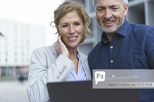 Smiling businesswoman with businessman sharing tablet PC