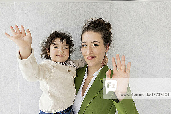 Happy mother and daughter waving at camera