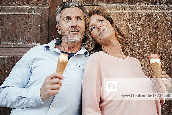 Contemplative mature couple with ice cream in front of door