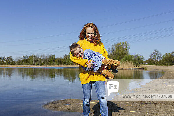 Glückliche Frau mit Sohn genießt sonnigen Tag am Seeufer