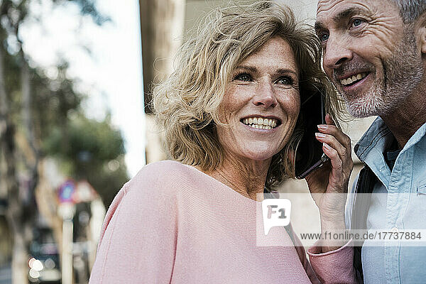 Happy woman talking on smart phone by man