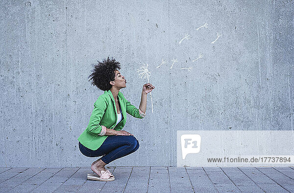 Crouching woman blowing painted blow ball flower