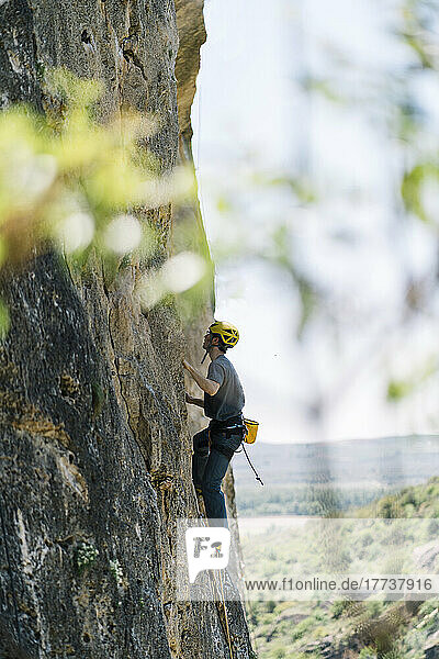 Determined man climbing mountain rock wall