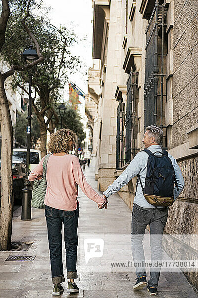 Mature couple walking on footpath in city
