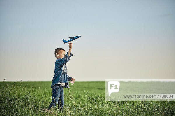 Junge wirft am Wochenende Flugzeugspielzeug in Feld