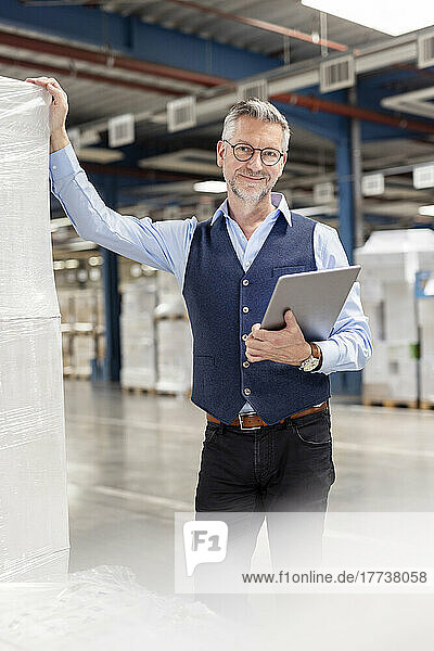 Smiling manager with tablet PC standing in warehouse