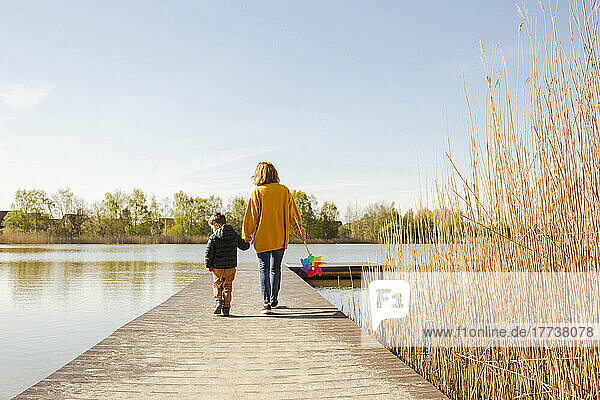 Mother and son walking on jetty over lake