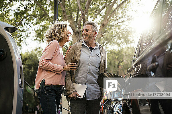 Cheerful couple talking at charging station