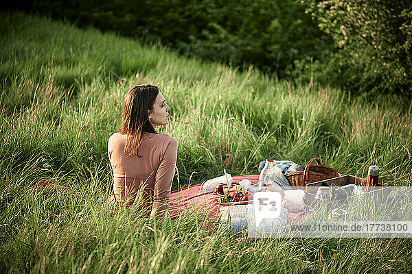 Contemplative woman sitting in field on weekend
