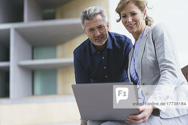 Businesswoman sharing laptop with businessman