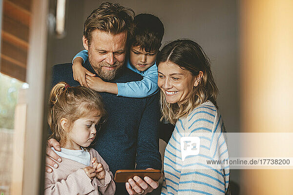 Glücklicher Mann teilt Smartphone mit Familie  gesehen durch das Fenster
