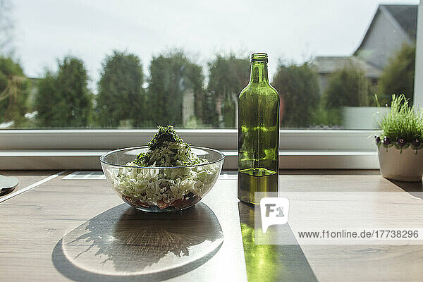 Salatschüssel und Flasche Olivenöl am Fenster