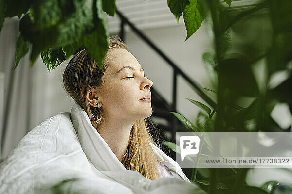Woman with eyes closed practicing breathing exercise at home