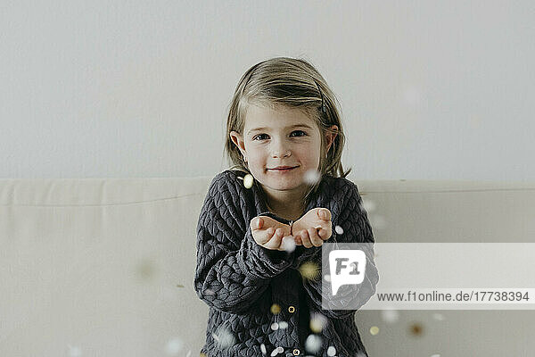 Cute girl with hands cupped playing with confetti