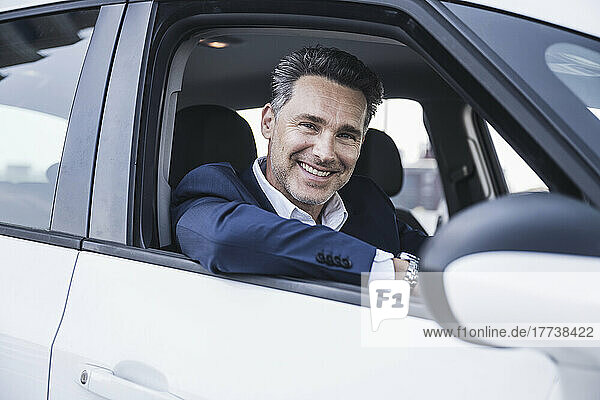 Happy businessman sitting in car